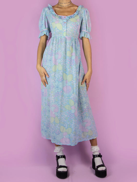 This vintage 1970s blue floral midi dress is pure pastel prairie charm. Made from lightweight semi-sheer fabric with an allover print in soft pastel tones. Features a square neckline with ruffle trim, puff sleeves with frilled cuffs, and a button-front bodice. The empire waist and flowing midi length create a gentle, romantic silhouette. Perfect for spring picnics, cottagecore styling, or vintage lovers drawn to sweet, feminine nostalgia.