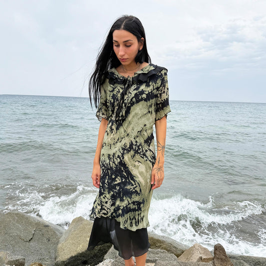 This vintage 90s midi dress features a black and green tie-dye pattern with a ruffled neckline. The short sleeves and flowy layered hem make it ideal for summer festivals, boho gatherings, or dark fairy-inspired looks. A unique Italian-made piece, perfect for forest parties or artistic styling. Made in Italy from lightweight non-stretch fabric. Excellent vintage condition.