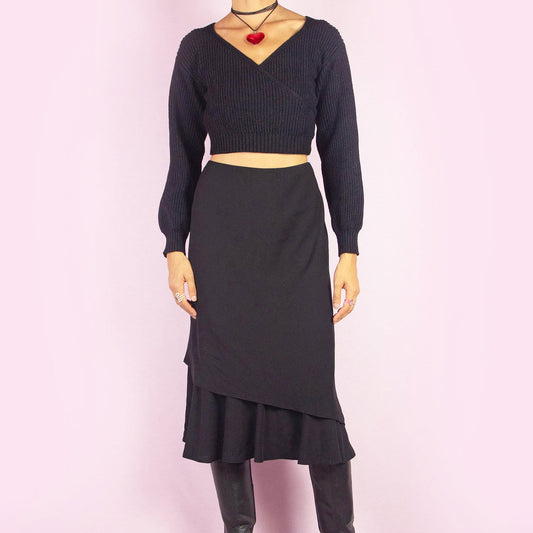The Vintage 90s Black Layered Midi Skirt showcases a layered design with a flared underlayer peeking out for an elegant silhouette. Featuring an elastic waist, this midi-length skirt is perfect for both office wear and evening occasions.