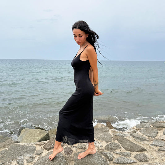This vintage 90s black midi dress features a minimalist slip silhouette. Made in Spain from a stretchy polyester mesh blend, it offers comfort and versatility, perfect as a casual summer staple, layered day look, or elevated night-out essential. A timeless piece for minimalist wardrobes. Excellent vintage condition.