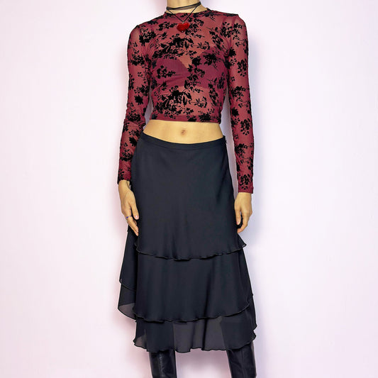The Vintage 90s Black Layered Tiered Skirt features a flowy, tiered design with cascading chiffon-like layers. It includes a side zipper closure. Its versatile length and elegant style make it perfect for both casual outings and evening parties. Excellent vintage condition.