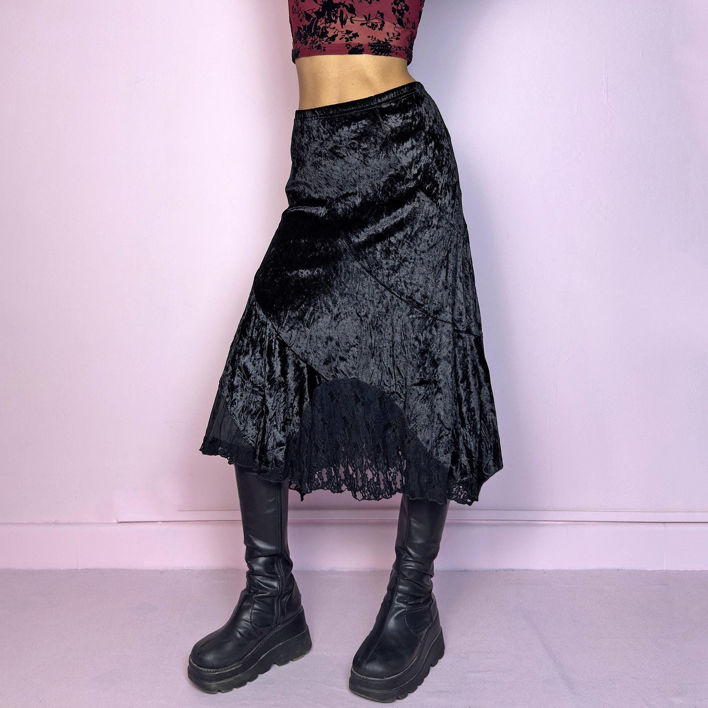 The Vintage 90s Black Velvet Asymmetric Skirt features a velvet fabric with an elegant asymmetrical hemline adorned with lace detailing for a touch of whimsy and an elastic waist. Its romantic and gothic-inspired design. Adult World Shop