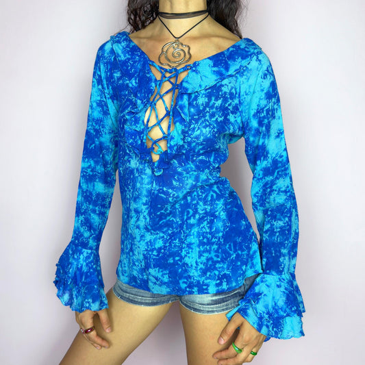 This vintage 90s blue tie dye top features dramatic ruffle cuffs, a deep lace-up neckline, and soft cotton-blend fabric in vibrant psychedelic tones. Designed with long sleeves it channels boho, hippie, and festival energy with bold originality. Lightweight and breathable, perfect for summer layering or statement styling. A rare archival blouse that captures wild 90s freedom. Excellent vintage condition.