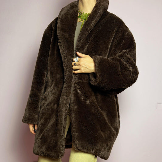 The Vintage 90s Brown Faux Fur Coat is a luxurious and cozy statement piece. Featuring a soft plush texture, and a deep chocolate brown hue, this coat exudes effortless elegance and warmth. Designed with a relaxed fit, pockets, and a hidden hook closure, it&#39;s perfect for layering over casual or dressed-up winter outfits. Made in Spain. adult world shop