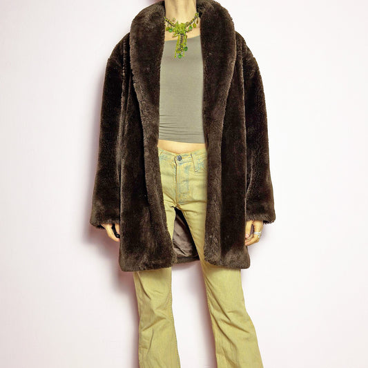 The Vintage 90s Brown Faux Fur Coat is a luxurious and cozy statement piece. Featuring a soft plush texture, and a deep chocolate brown hue, this coat exudes effortless elegance and warmth. Designed with a relaxed fit, pockets, and a hidden hook closure, it's perfect for layering over casual or dressed-up winter outfits. Made in Spain from a polyester faux fur blend. Great vintage condition.