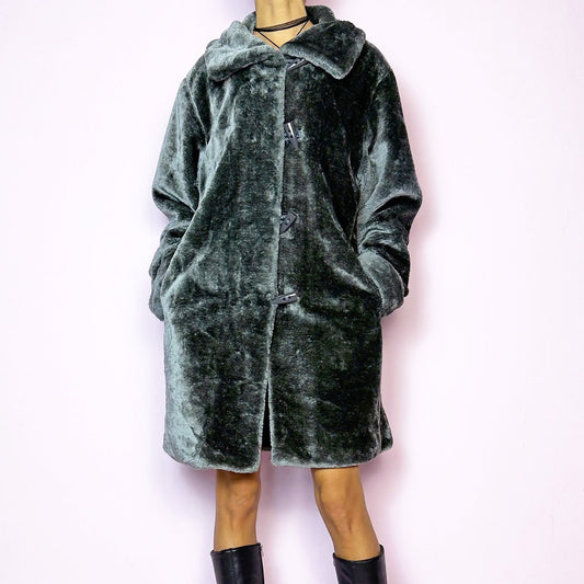 The Vintage 90s Gray Faux Fur Coat is a cozy and stylish outerwear piece featuring a plush faux fur design, a toggle-front closure, a wide collar, and pockets. Perfect for your winter wardrobe. Great vintage condition.