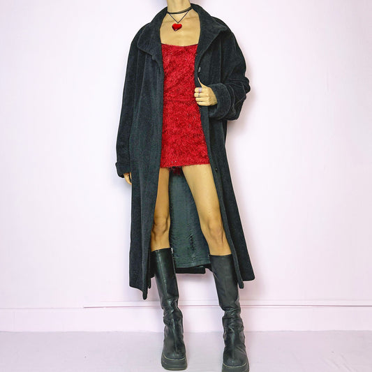 The Vintage 90s Gray Lambswool Maxi Coat features a dark gray, almost black, lambswool, angora and viscose blend, offering softness and warmth. It includes pockets and a button front closure. The long silhouette ensures a comfy and cozy fit, making it perfect for chilly winter days. Great vintage condition.