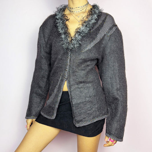 The Vintage 90s Gray Shaggy Trim Cardigan is a unique statement knitwear piece, featuring a soft knit fabric. Designed with a shaggy, hairy-textured trim along the V-neckline, subtle beaded embellishments, and button closure, this cardigan is perfect for cozy winter outfits. Great vintage condition.