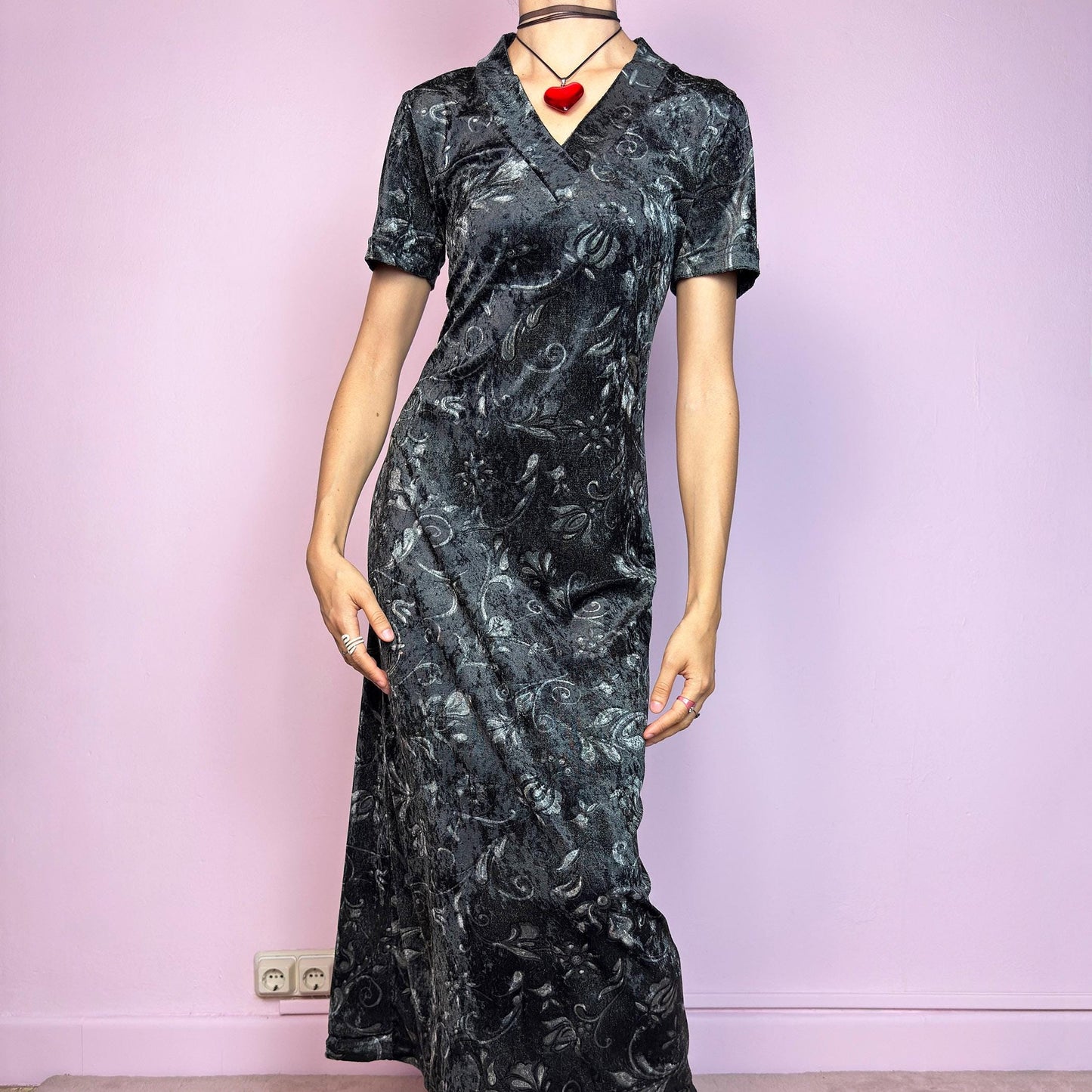 The Vintage 90s Gray Velvet Midi Dress is a moody and elegant 90s piece made from soft, stretchy dark gray velvet with a baroque-style printed pattern. Features a flattering V-neckline, short sleeves, and a sleek longline silhouette. The velvety fabric gives it a luxurious feel while staying comfy. Perfect for witchy aesthetics, gothic romance, or vintage night-out looks.