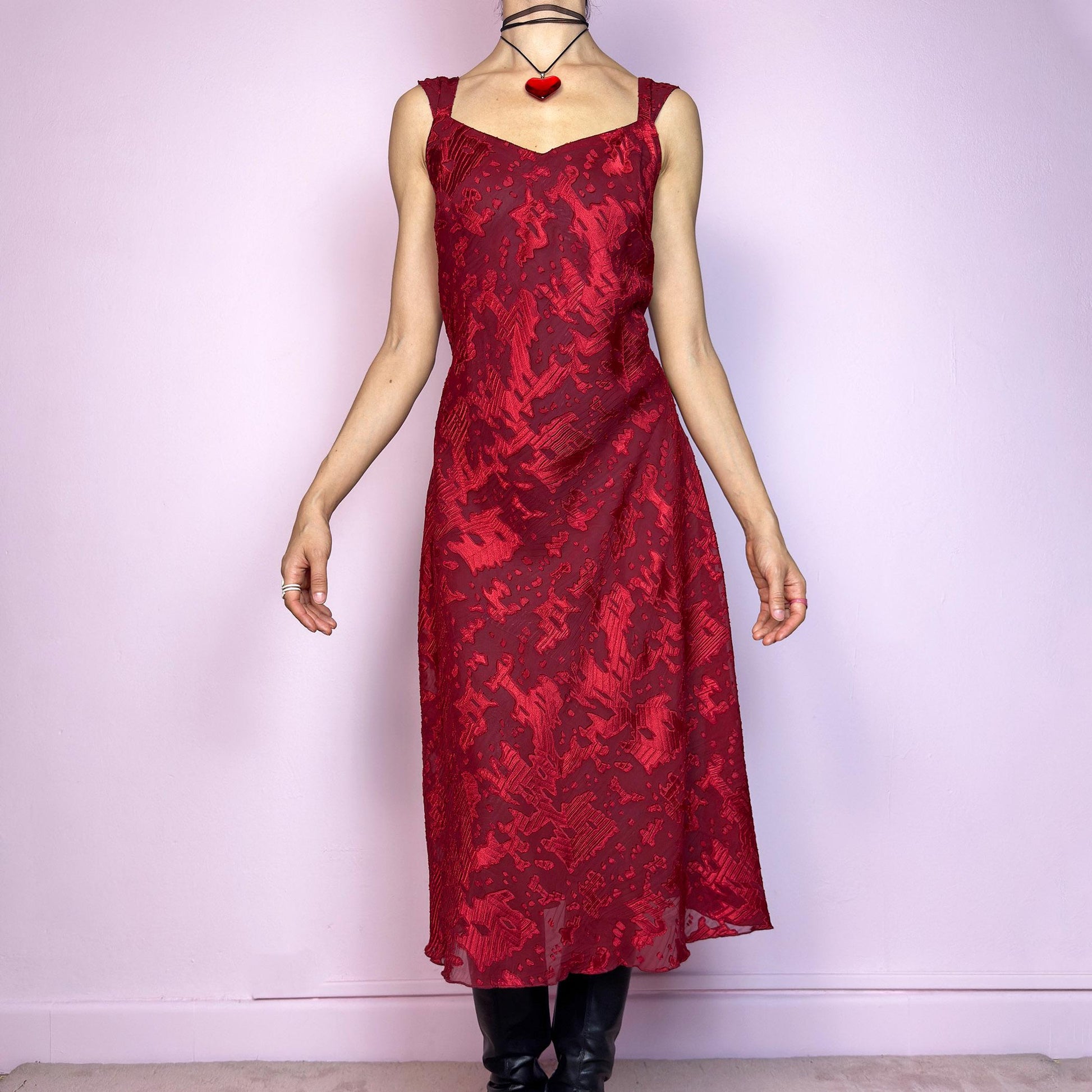 The Vintage 90s Maroon Textured Midi Dress is a romantic and striking piece in a rich maroon tone with abstract textured patterns and a sheer overlay. Designed with wide straps, a flattering sweetheart neckline, and a flowy midi-length cut. The semi-sheer fabric adds depth while the inner lining provides comfort. Perfect for formal events, romantic nights, or gothic glam looks. Elegant, timeless, and effortlessly dramatic. Excellent vintage condition.