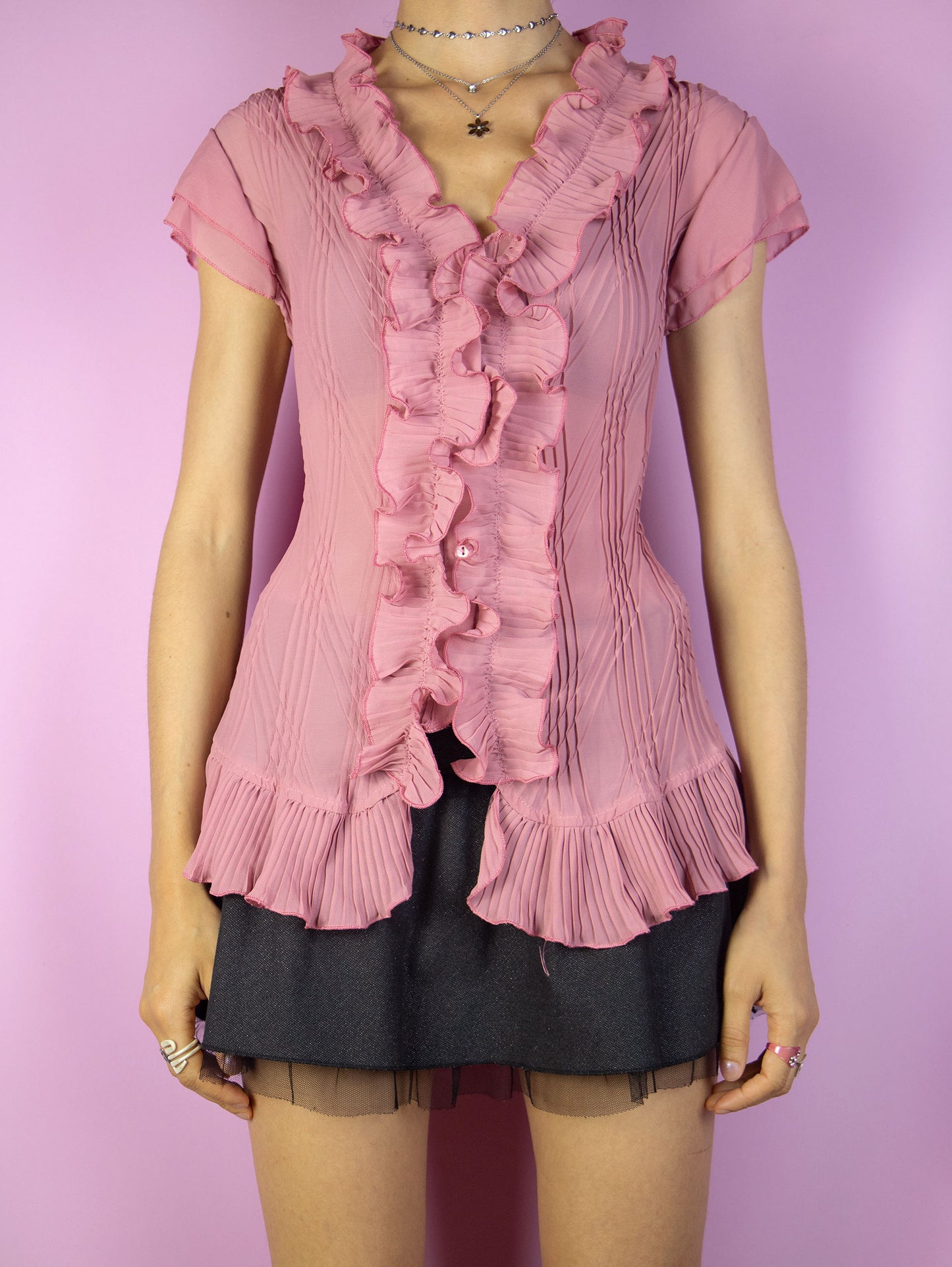 This vintage 90s pink semi-sheer pleated blouse features delicate ruffles along the neckline and hem, a sleeveless cut, and button-front closure. Its airy fabric and romantic detailing evoke rococo and coquette summer elegance, perfect for whimsical events or refined formal styling. A dreamy and feminine archive piece. Made from a lightweight polyester blend. Excellent vintage condition.