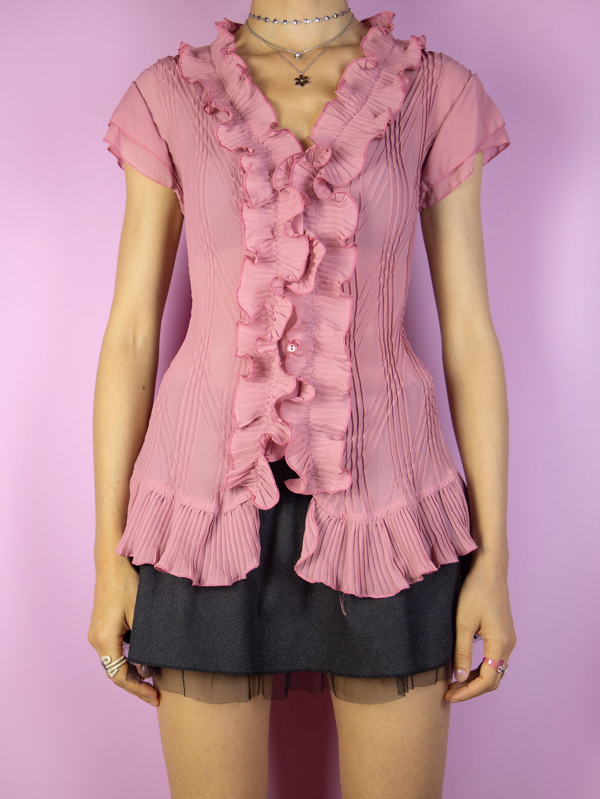 This vintage 90s pink semi-sheer pleated blouse features delicate ruffles along the neckline and hem, a sleeveless cut, and button-front closure. Its airy fabric and romantic detailing evoke rococo and coquette summer elegance, perfect for whimsical events or refined formal styling. A dreamy and feminine archive piece. Made from a lightweight polyester blend. Excellent vintage condition.