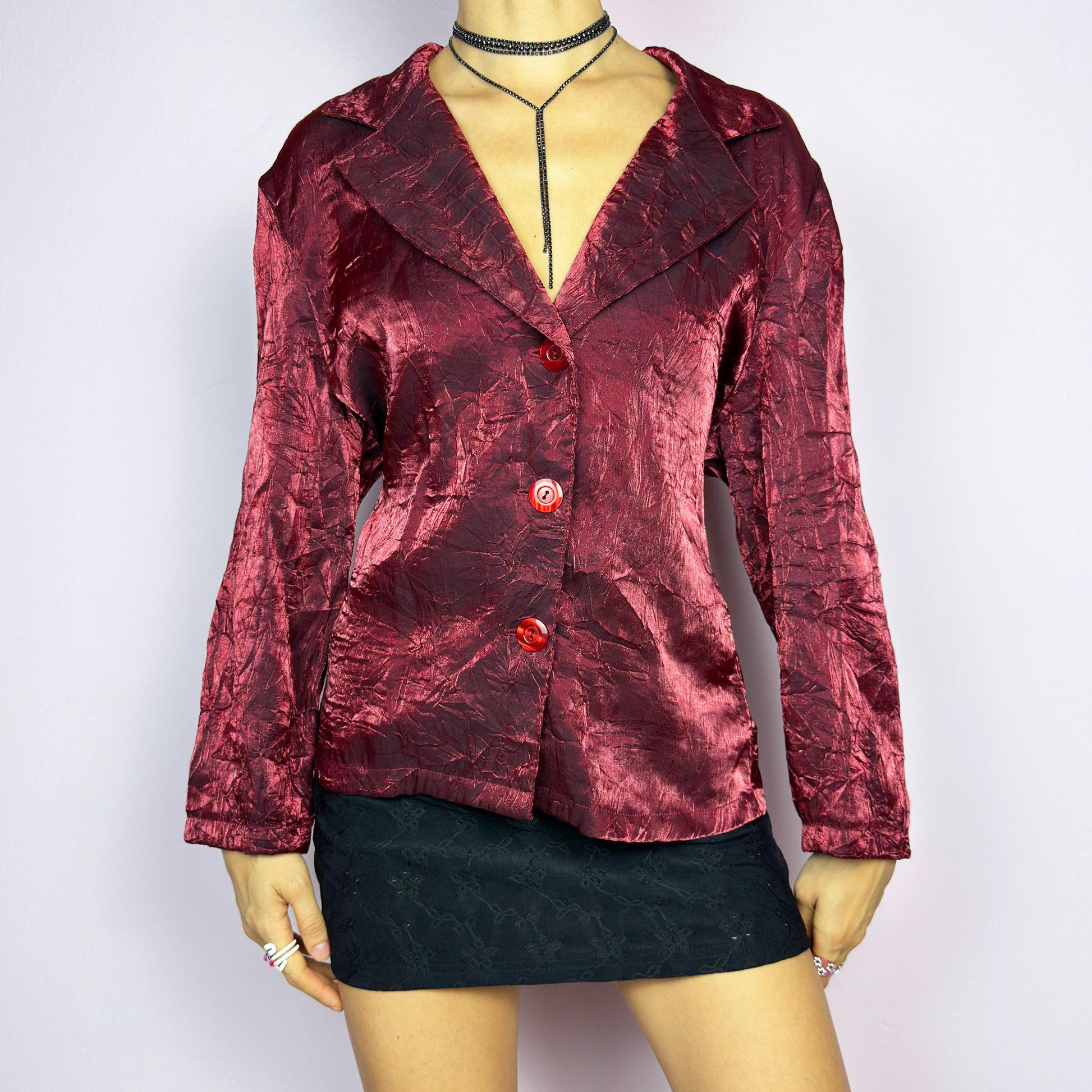 The Vintage 90s Red Iridescent Jacket is a striking and glamorous piece featuring a textured, crinkled design with a luxurious, iridescent sheen. This button-up jacket showcases a deep red tone, wide lapels, and bold red buttons for a dramatic look. Perfect for evening outings or as a statement piece to elevate your outfit. Excellent vintage condition.