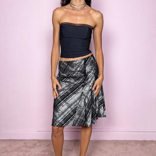 This vintage 90s silver-gray check plaid skirt features structured pleats, a side zipper closure, and a shiny futuristic finish. Made in Germany from a polyester-acetate blend, it combines minimal preppy style with avant-garde elegance. Perfect for office wear, city looks, or coquette-inspired outfits with a modern twist. No stretch. Fits high-waisted for size L. Excellent vintage condition.