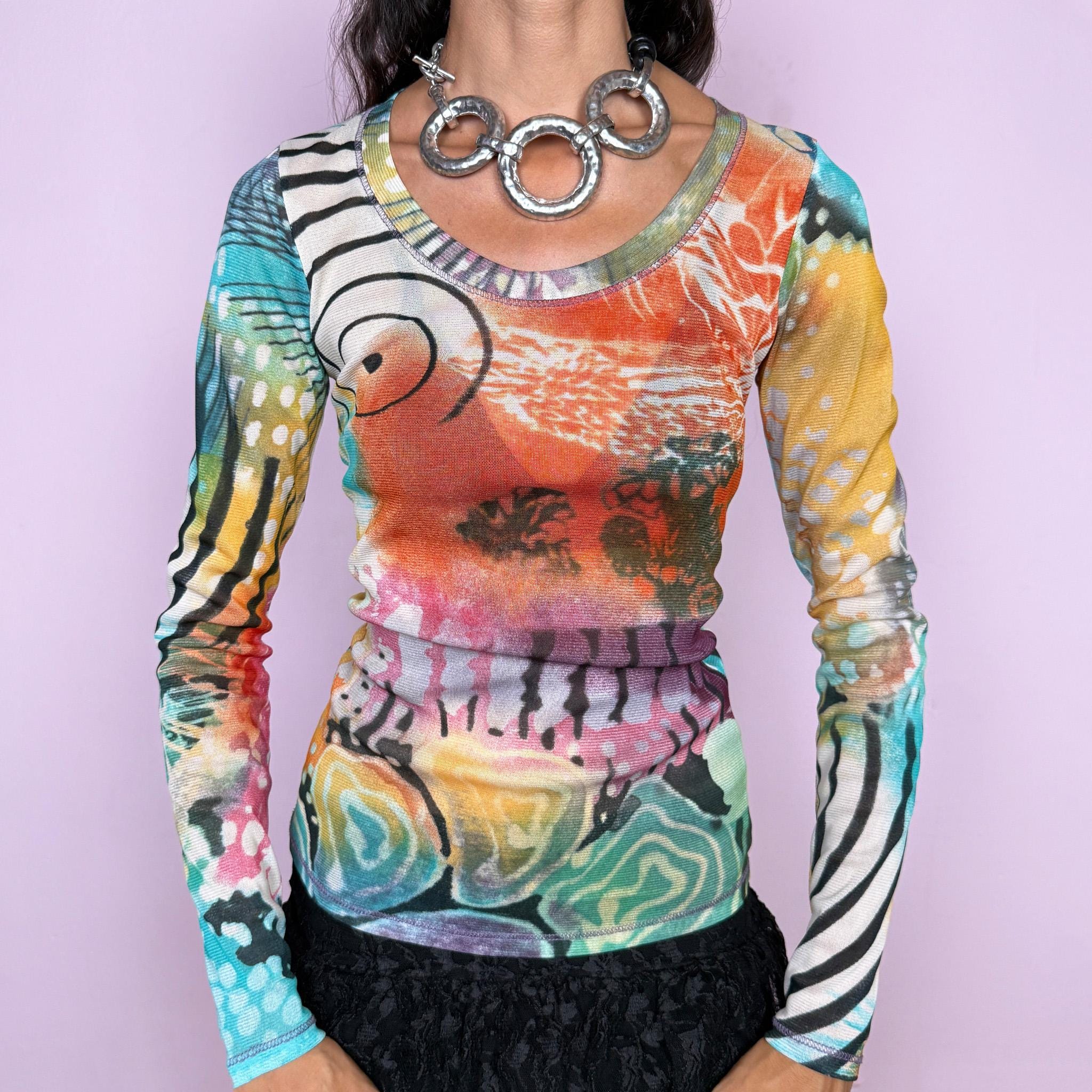 Vintage 2000s long-sleeve mesh top featuring a vibrant abstract graphic print mixing turquoise, orange, yellow, pink, and green with contrasting organic, striped, and painterly motifs. Designed with a fitted silhouette, scoop neckline, and semi-sheer lightweight mesh construction. Stretchy fabric creates a close, second-skin fit. A strong maximalist Y2K piece with an art-print feel. Made in France by a French brand from 100% polyester. Excellent vintage condition.