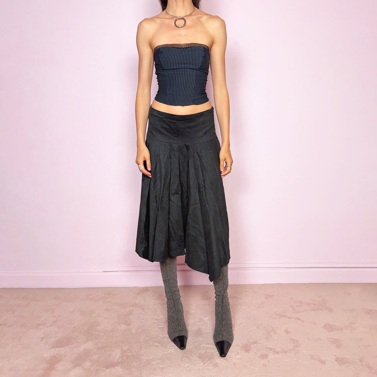 Vintage 2000s black soft faux-suede style midi skirt with a dark avant-garde minimalist look. Features a flared silhouette, asymmetric handkerchief-style hem, side zip closure, and a structured non-stretch fit. Can be worn mid-rise for size S or lower-rise for size XS. Made from polyester and acetate. From a Swedish brand. Excellent vintage condition.