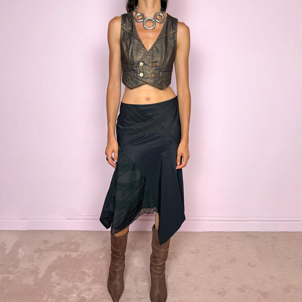 Vintage 2000s black asymmetric midi skirt featuring a deconstructed patchwork construction that combines fine pinstripe panels with contrasting fabric sections and subtle lace-trim detailing. Designed with a dramatic irregular handkerchief-style hem and a dark avant-garde Y2K silhouette. Features a side zip closure and no stretch. Can be worn high-waisted for size M or mid- to lower-rise for sizes S–XS.