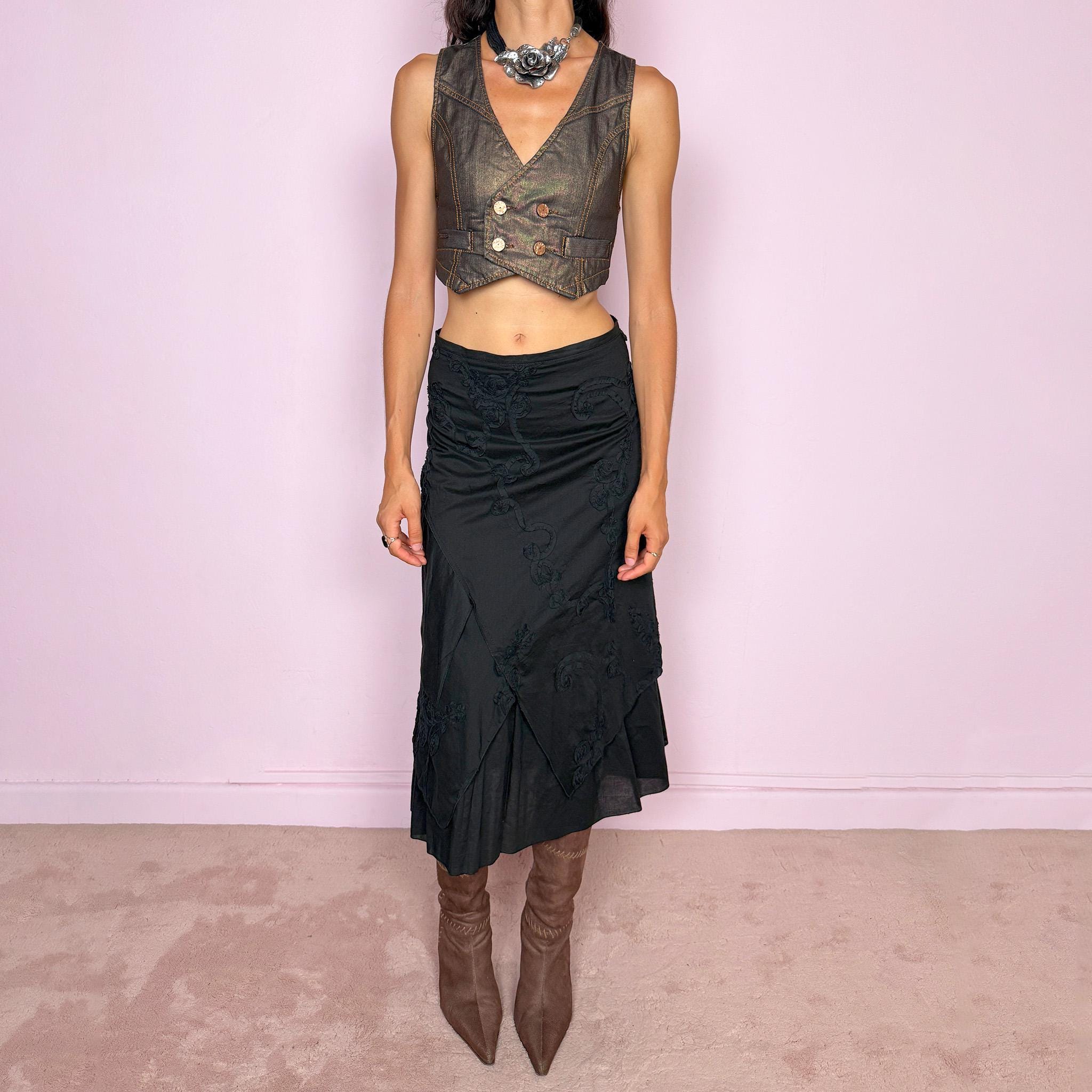 Vintage 2000s black midi skirt crafted from 100% cotton with layered asymmetric panels and tonal floral embroidery appliqué. Features a back zip closure and no stretch. Ideal for bohemian, dark fairy, or summer styling. Can be worn high-waisted for size S or slightly lower on the waist for sizes XS–XXS. Made in France by a French brand and fully lined in 100% polyester. Excellent vintage condition.