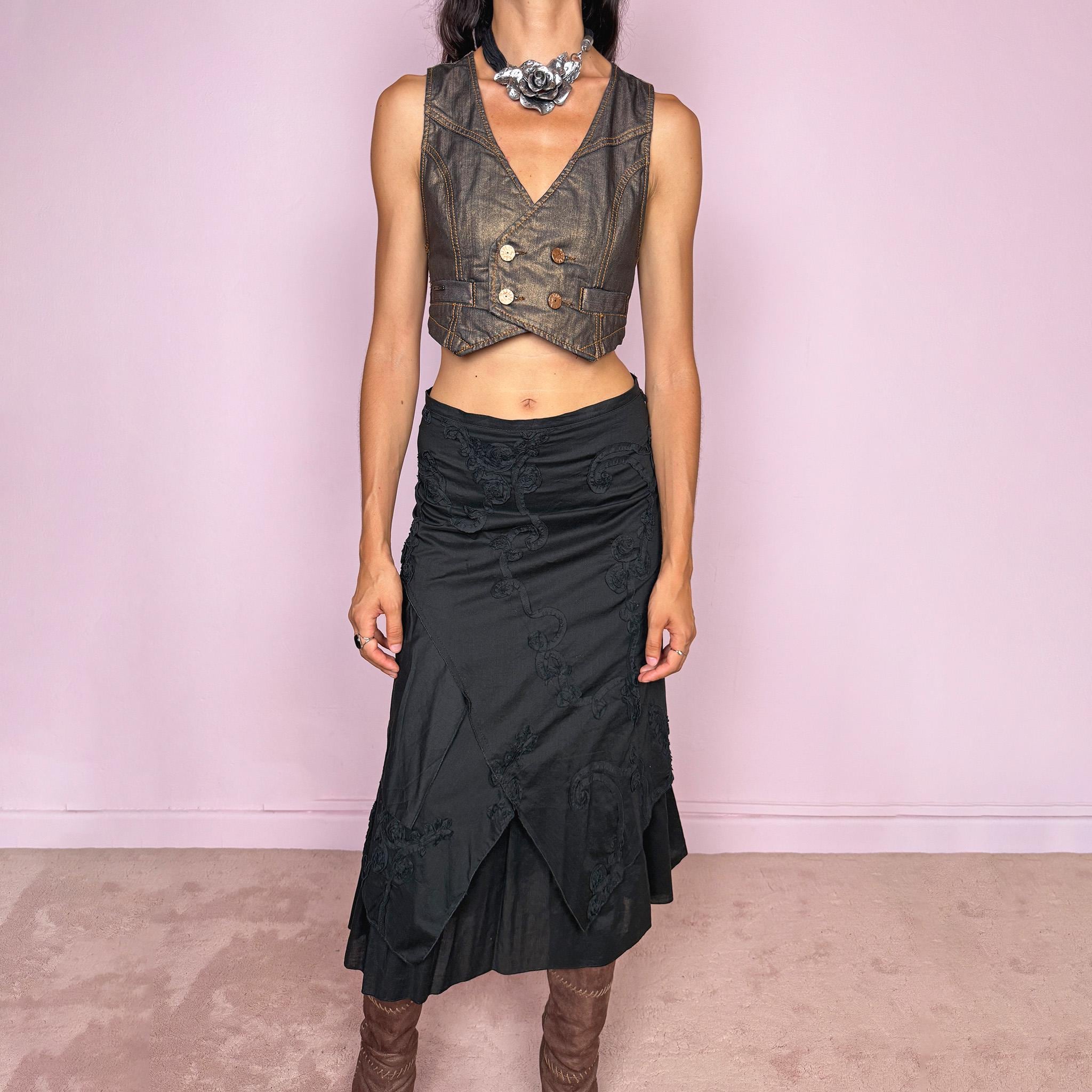 Vintage 2000s black midi skirt crafted from 100% cotton with layered asymmetric panels and tonal floral embroidery appliqué. Features a back zip closure and no stretch. Ideal for bohemian, dark fairy, or summer styling. Can be worn high-waisted for size S or slightly lower on the waist for sizes XS–XXS. Made in France by a French brand and fully lined in 100% polyester. Excellent vintage condition.