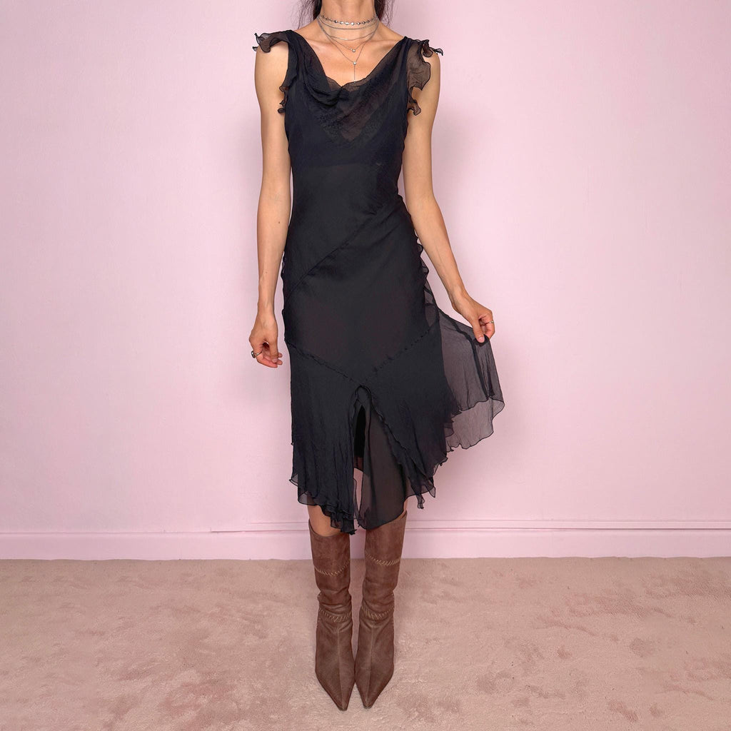 Vintage 2000s black midi dress with a romantic draped silhouette and semi-sheer layered construction. Designed with a cowl-style neckline, delicate ruffled cap sleeves, fitted waist, front slit detail, and fluid layered asymmetrical hem for an elegant dark evening look. The outer layer looks and feels like silk, but all labels are missing, so the exact fabric composition is unknown. Excellent vintage condition.
