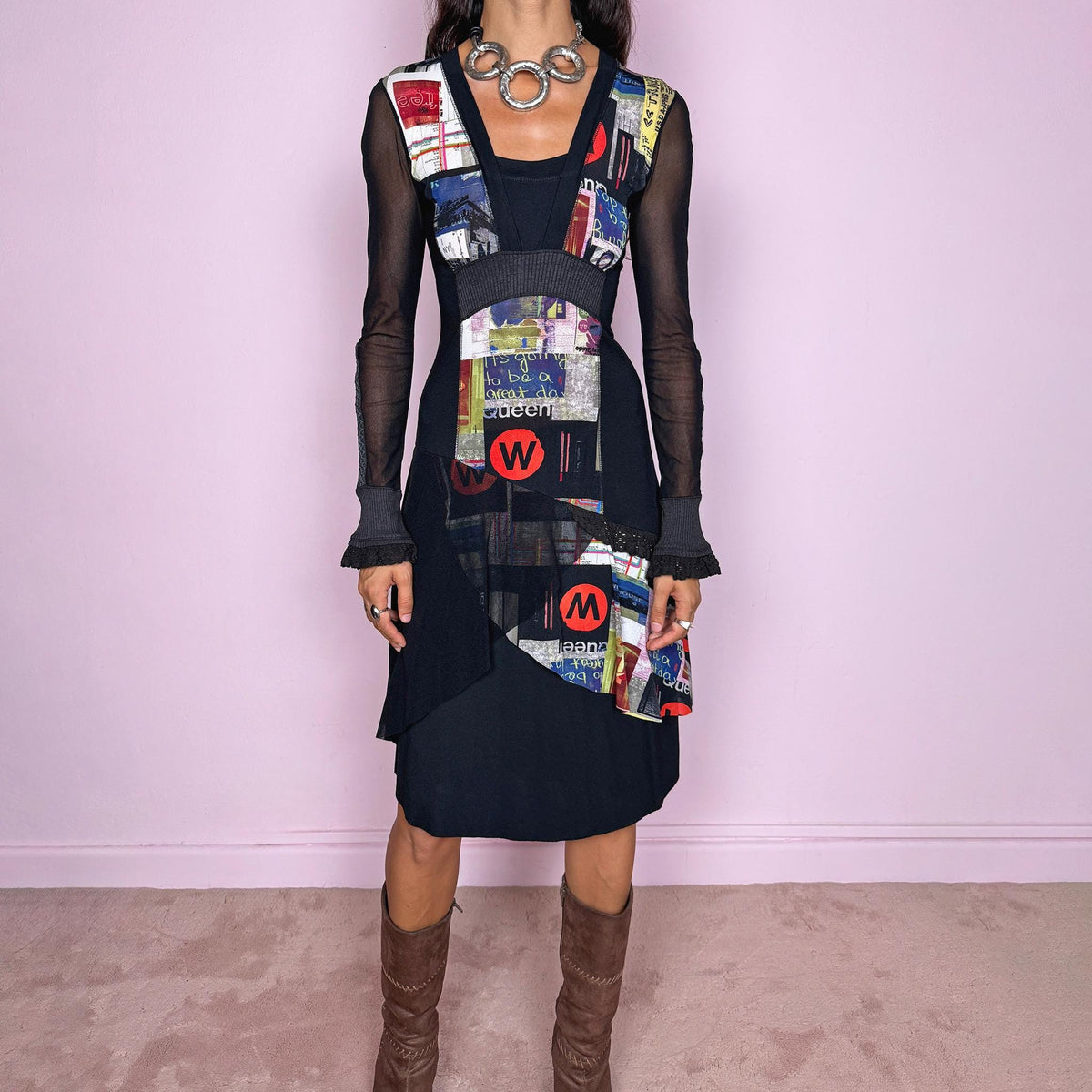 Vintage 2000s black midi dress featuring a stretchy fitted base with semi-sheer long sleeves and a layered deconstructed graphic construction through the front. Designed with an asymmetric mix of collage-style printed panels, text and bold multicolor motifs, plus contrasting ribbed sections and ruffled cuff details. The combination of sheer fabric, irregular paneling and graphic artwork gives it an avant-garde Y2K art-to-wear look.