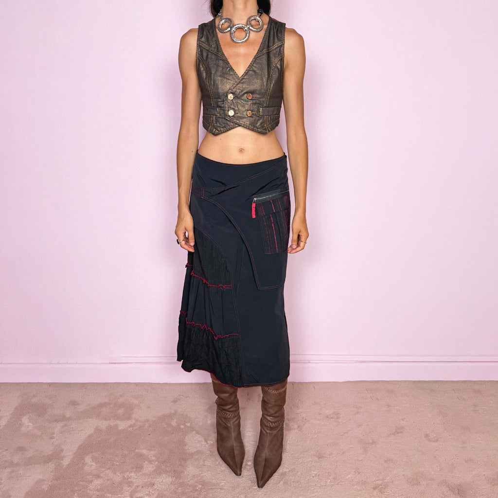 Vintage 2000s black deconstructed midi skirt with a structured, non-stretch feel. Features asymmetric paneled construction, contrasting red topstitching, a utility-inspired zip pocket, and layered crinkled fabric inserts. Finished with a back zip closure. A distinctive dark avant-garde piece with a dystopian, futuristic Y2K feel. Can be worn high-waisted for size M or mid- to lower-rise for sizes S–XS. Made in France by a French brand.