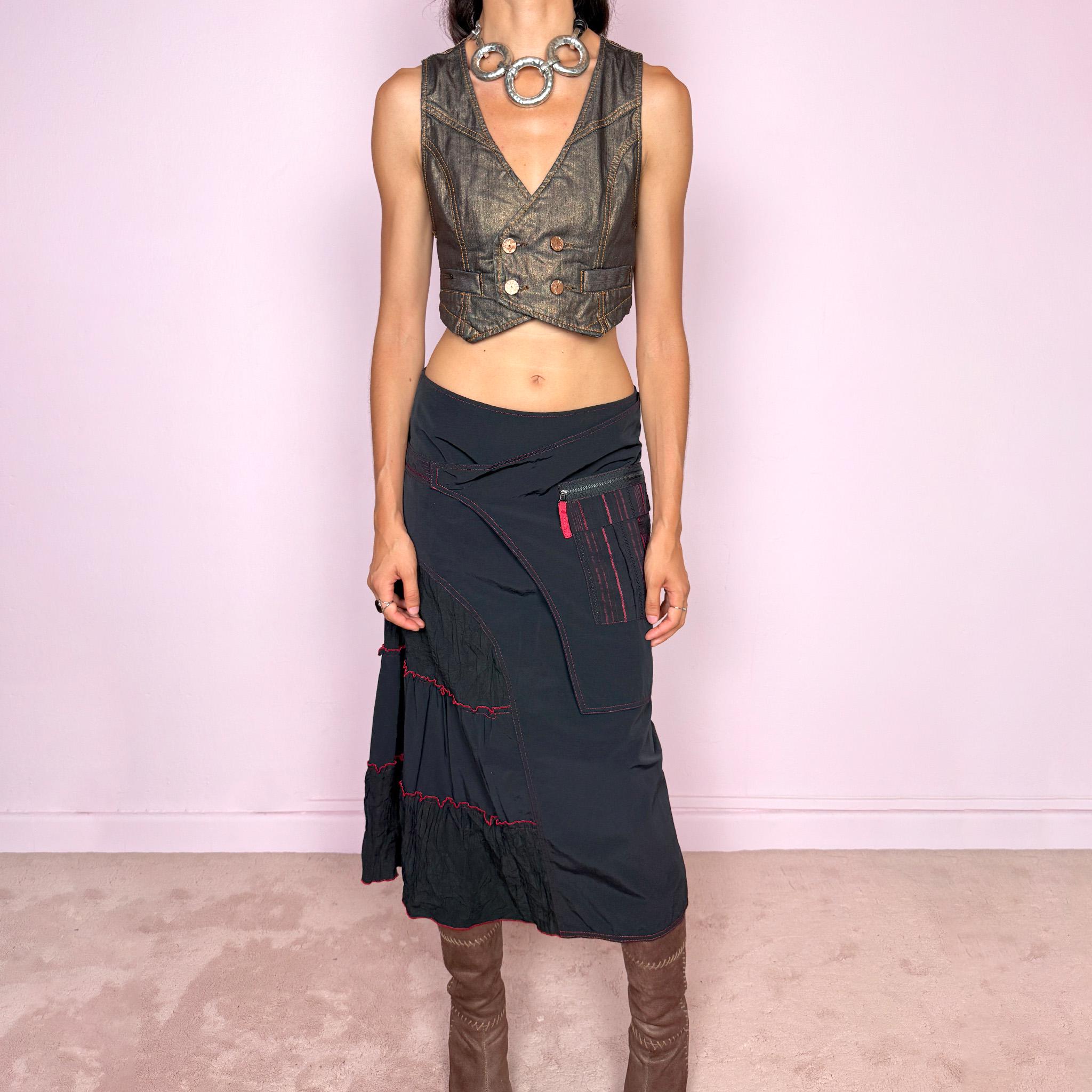 Vintage 2000s black deconstructed midi skirt with a structured, non-stretch feel. Features asymmetric paneled construction, contrasting red topstitching, a utility-inspired zip pocket, and layered crinkled fabric inserts. Finished with a back zip closure. A distinctive dark avant-garde piece with a dystopian, futuristic Y2K feel. Can be worn high-waisted for size M or mid- to lower-rise for sizes S–XS. Made in France by a French brand.