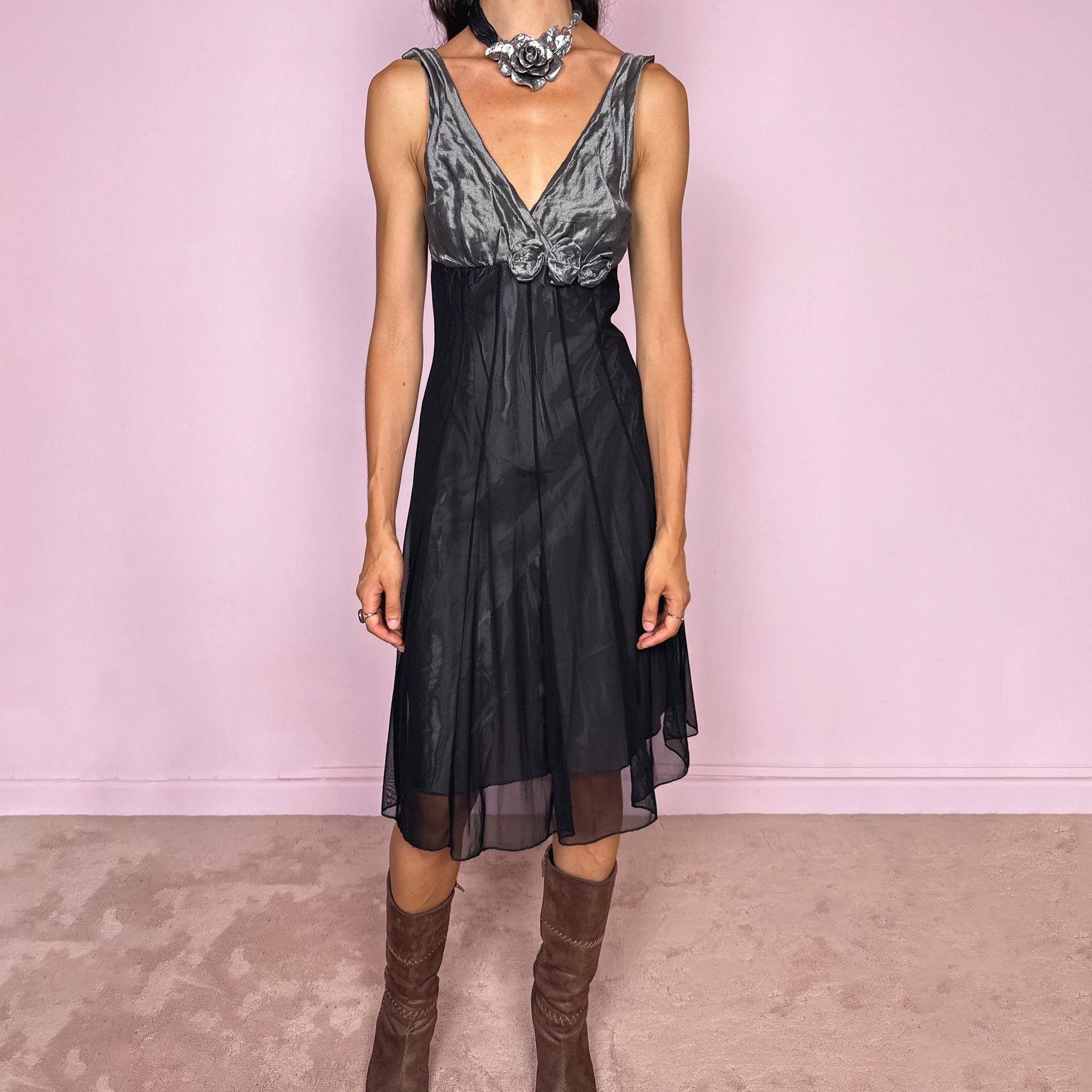 Vintage 2000s sleeveless midi dress made in Italy. Designed with a fitted empire-line silhouette, a deep V-neckline, and a contrasting metallic grey bodice with a soft gathered texture and dimensional rosette appliqués beneath the bust. The black semi-sheer skirt falls fluidly, creating an elegant dark romantic silhouette ideal for evenings and parties. Made from a non-stretch polyester, polyamide, cotton, and metal blend. Excellent vintage condition.