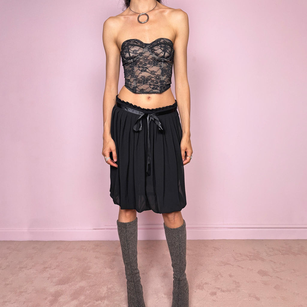 Vintage 2000s black bubble hem midi skirt featuring a pleated silhouette with side zip closure, front tie detail, and voluminous bubble hem. Romantic yet minimal with a subtle coquette party mood, ideal for formal occasions, evening looks, or darker feminine everyday styling. Can be worn high waisted for M or lower rise for S. From a French brand. Excellent vintage condition.