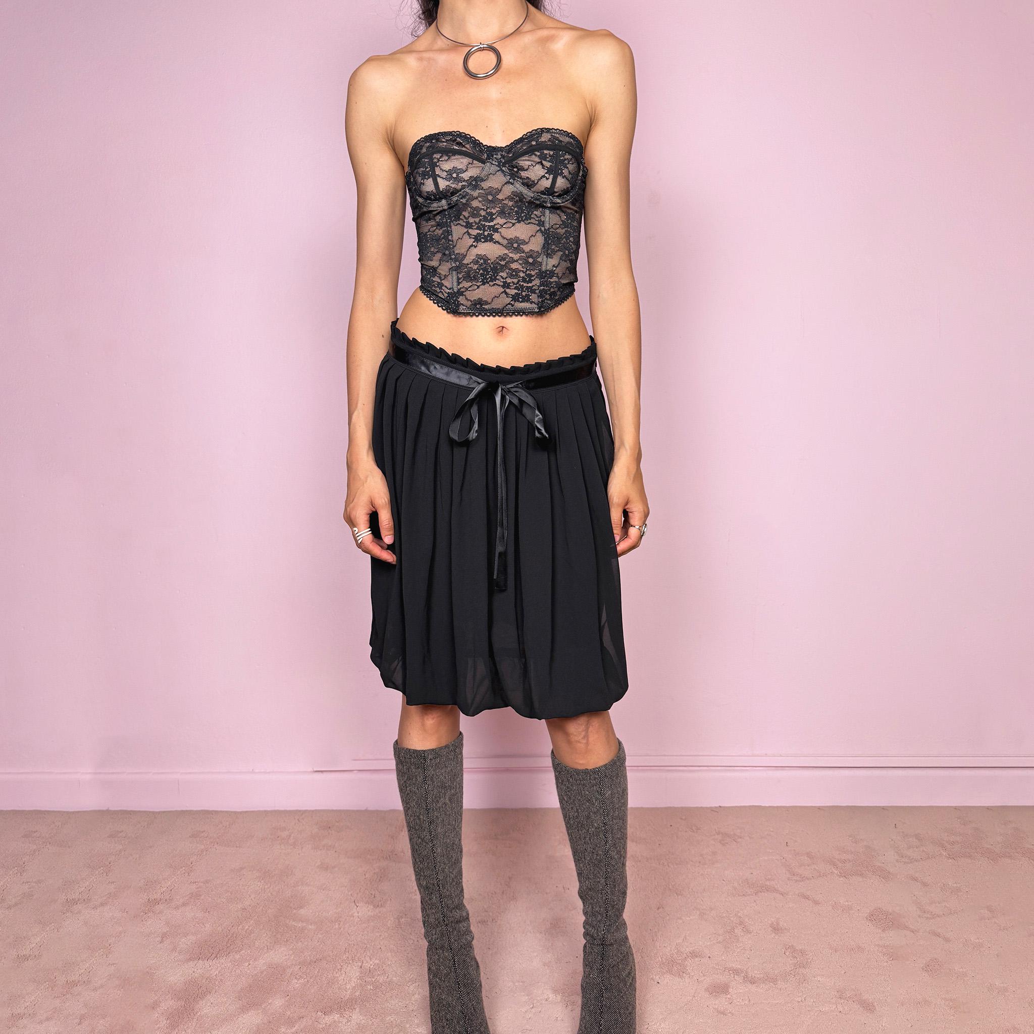Vintage 2000s black bubble hem midi skirt featuring a pleated silhouette with side zip closure, front tie detail, and voluminous bubble hem. Romantic yet minimal with a subtle coquette party mood, ideal for formal occasions, evening looks, or darker feminine everyday styling. Can be worn high waisted for M or lower rise for S. From a French brand. Excellent vintage condition.
