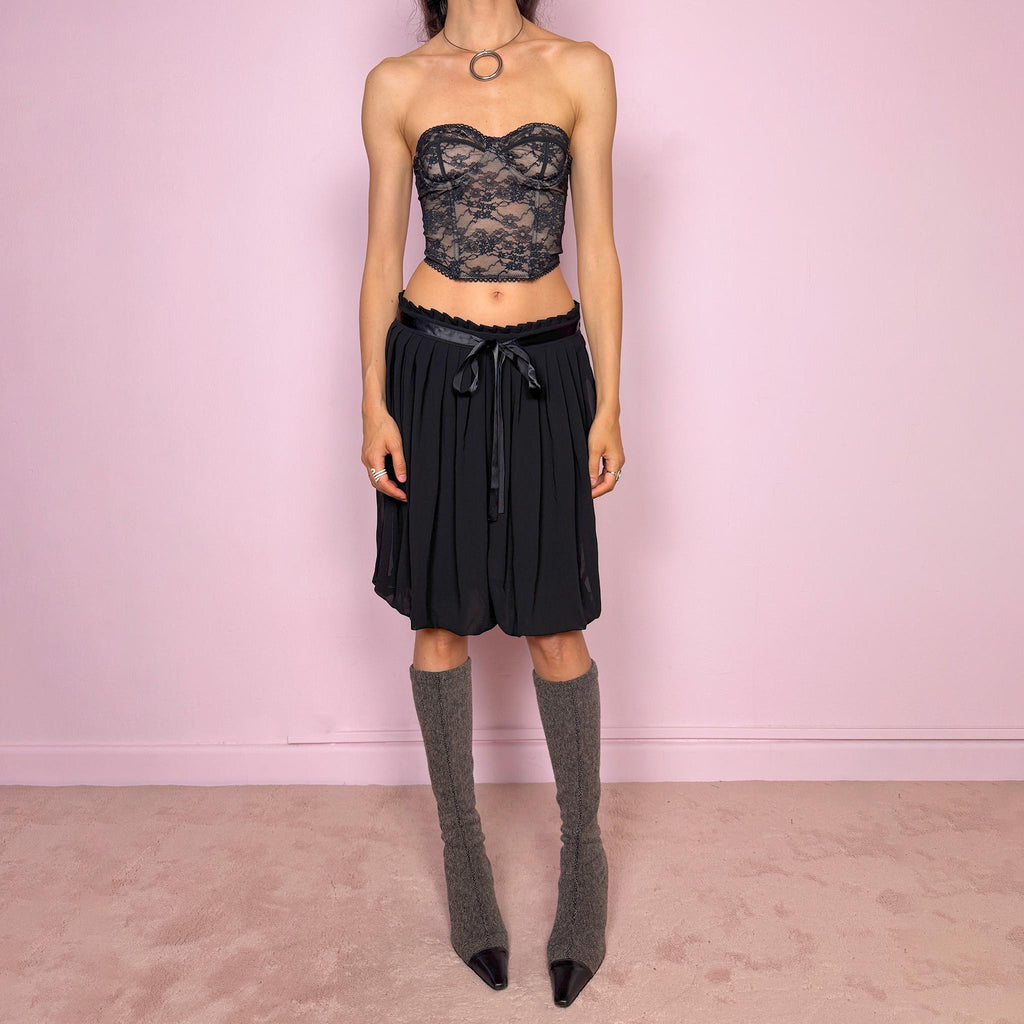 Vintage 2000s black bubble hem midi skirt featuring a pleated silhouette with side zip closure, front tie detail, and voluminous bubble hem. Romantic yet minimal with a subtle coquette party mood, ideal for formal occasions, evening looks, or darker feminine everyday styling. Can be worn high waisted for M or lower rise for S. From a French brand. Excellent vintage condition.