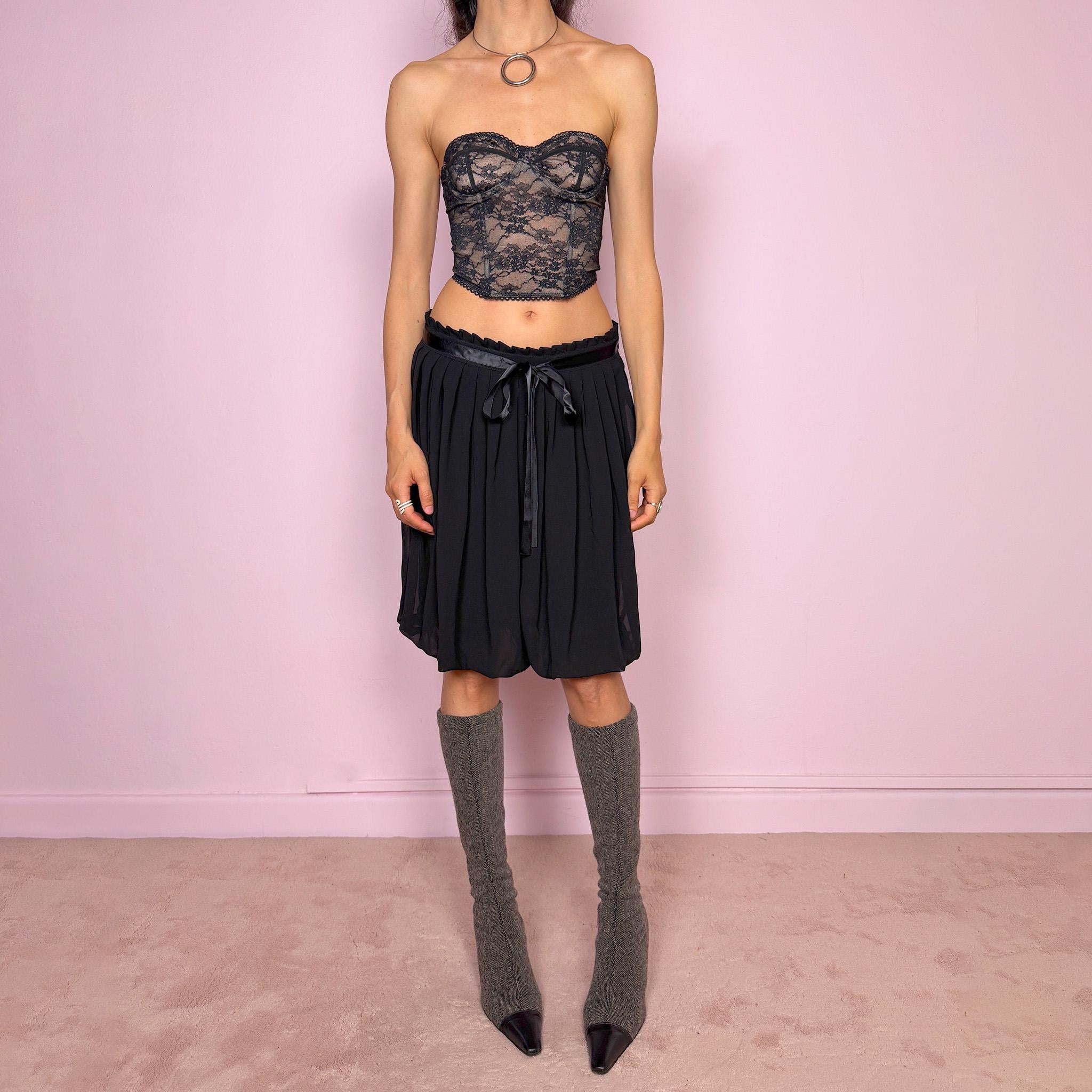 Vintage 2000s black bubble hem midi skirt featuring a pleated silhouette with side zip closure, front tie detail, and voluminous bubble hem. Romantic yet minimal with a subtle coquette party mood, ideal for formal occasions, evening looks, or darker feminine everyday styling. Can be worn high waisted for M or lower rise for S. From a French brand. Excellent vintage condition.