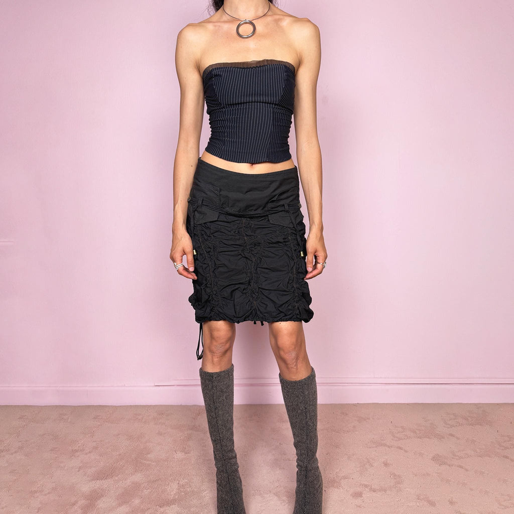 Vintage 2000s black ruched mini skirt crafted from 100% cotton with sculptural gathered texture, dimensional ruching, stitched lattice detailing, adjustable drawstring accents, back button closure, and no stretch. Dark Y2K cyber dystopian utility aesthetic. Can be worn mid rise for size S or lower rise for XS. Made in France from a French brand. Great vintage condition.