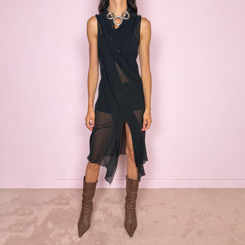 Vintage 2000s black semi-sheer midi dress with a fluid sleeveless silhouette, asymmetric draped panel construction, and a front opening that creates soft movement through the hem. The layered fabric falls in long sculptural lines across the body, giving the dress an elegant dark avant-garde feel. Brand, size, and composition labels are missing; the fabric feels like silk, but the exact composition cannot be confirmed. Great vintage condition.
