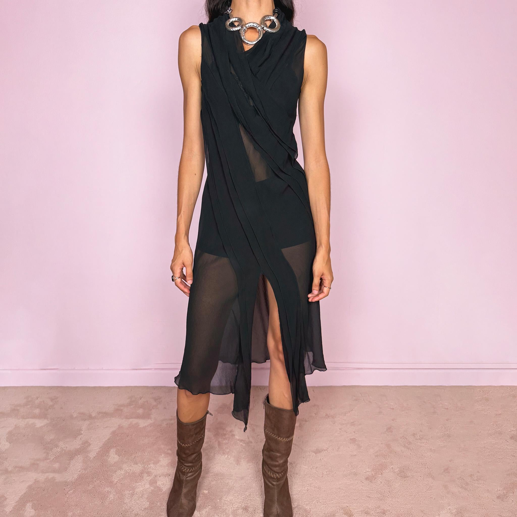 Vintage 2000s black semi-sheer midi dress with a fluid sleeveless silhouette, asymmetric draped panel construction, and a front opening that creates soft movement through the hem. The layered fabric falls in long sculptural lines across the body, giving the dress an elegant dark avant-garde feel. Brand, size, and composition labels are missing; the fabric feels like silk, but the exact composition cannot be confirmed. Great vintage condition.