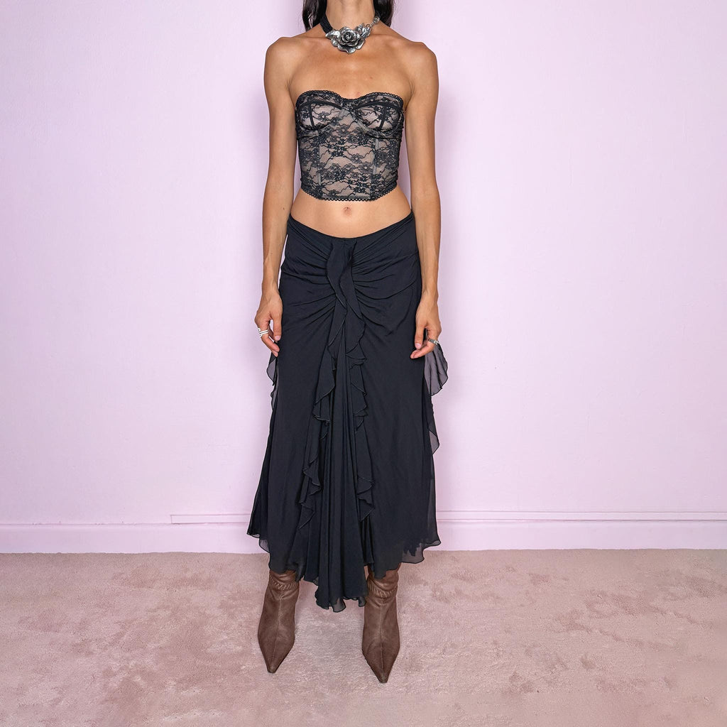 Vintage 2000s black silk midi skirt featuring soft ruching through the hips, cascading ruffle detailing down the front and sides, and a fluid flared hem for dramatic movement. Back zip closure and non-stretch. The layered silk construction and sculptural draping are ideal for elevated evening styling. Can be worn mid-rise for size M or lower on the waist for size S. Made in Italy by an Italian brand from 100% silk with a 100% polyester lining. Excellent vintage condition.