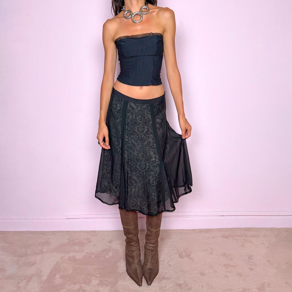 Vintage 2000s black silk A-line flared midi skirt crafted from 100% silk, with contrasting beige and black lining that subtly reveals an intricate dark floral paisley pattern through the outer fabric, a semi-sheer black overlay, and delicate black sequin trim along the edge. Elegant with a romantic eveningwear feel. Non-stretch with a side zip closure. Can be worn mid-rise for size M or lower-rise for size S. From a German brand. Excellent vintage condition.