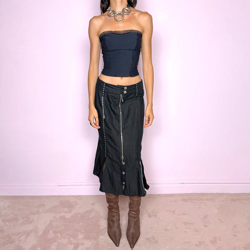 Vintage 2000s black midi skirt featuring an exposed full-length front zip, double-button waistband, and contrast white stitching throughout. The lower section opens into sculptural deconstructed panels with additional button and zip detailing, creating an asymmetric, utilitarian avant-garde feel. Can be worn high-waisted for size M or slightly lower on the waist for sizes S and XS. Non-stretch. Made in Holland by a Dutch brand from a structured blend of 52% cotton and 48% linen