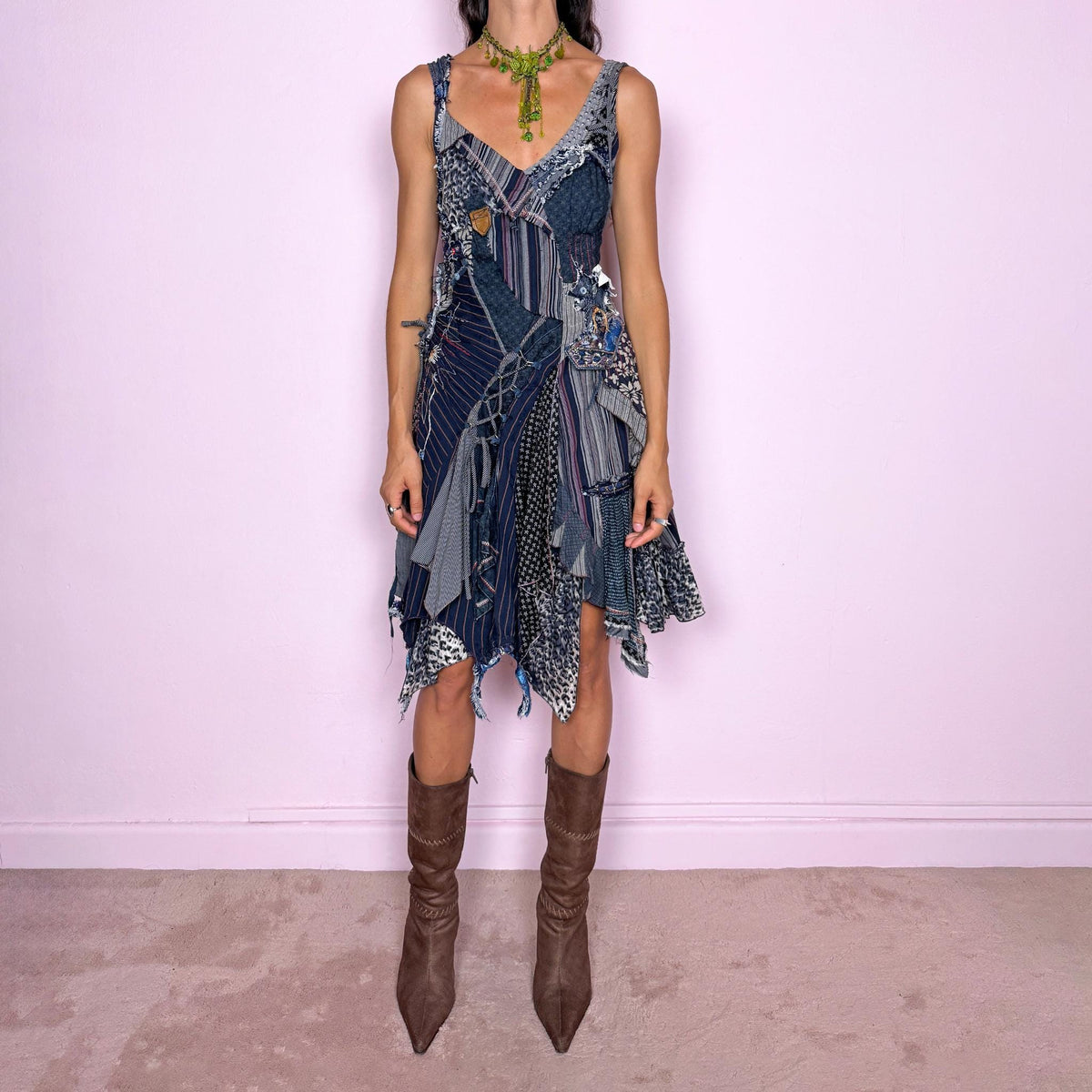 Vintage 2000s dark blue patchwork midi dress featuring an intricate deconstructed construction made from mixed pinstripe, floral, animal-print, and textured fabric panels. Designed with a deep V-neckline, fitted bodice, asymmetric layered skirt, exposed seams, raw-edge finishes, decorative stitching, lace-up detailing, and multiple draped panels throughout. Finished with a side zip closure. Non-stretch. For ragged-doll, bohemian, and avant-garde looks.