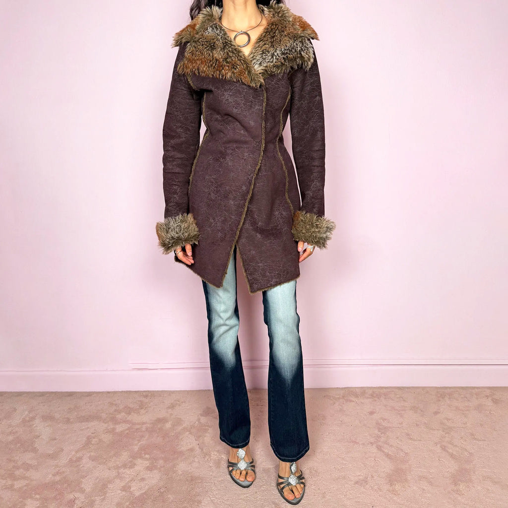Vintage 2000s brown Penny Lane-inspired coat featuring a fitted longline silhouette with a distressed faux-leather effect and dramatic oversized faux-fur trim at the collar and cuffs. Designed with contrast seam detailing, snap-button front closure and a matching fabric belt for an adjustable cinched waist. Crafted from a 50% acrylic and 50% polyester blend. Excellent vintage condition.