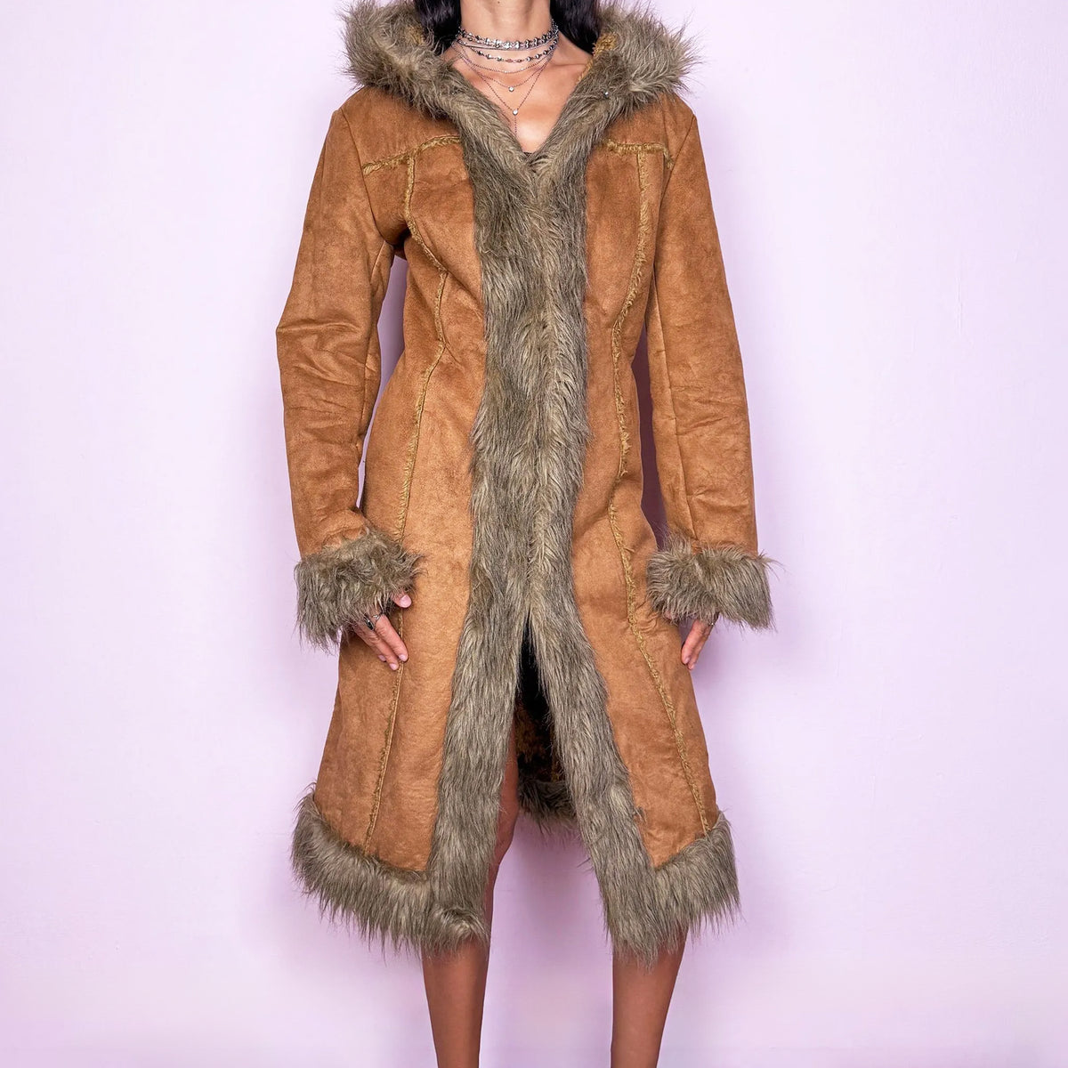 Vintage 2000s brown hooded Penny Lane coat in a faux-suede finish, featuring a long, fitted Afghan-inspired silhouette with plush beige faux-fur trim along the hood, front opening, cuffs, and hem. Designed with exposed seam detailing, a hidden hook-and-eye front closure, and side pockets for a distinctly Y2K bohemian look. The labels are missing, so the exact fabric composition is unknown. Great vintage condition.