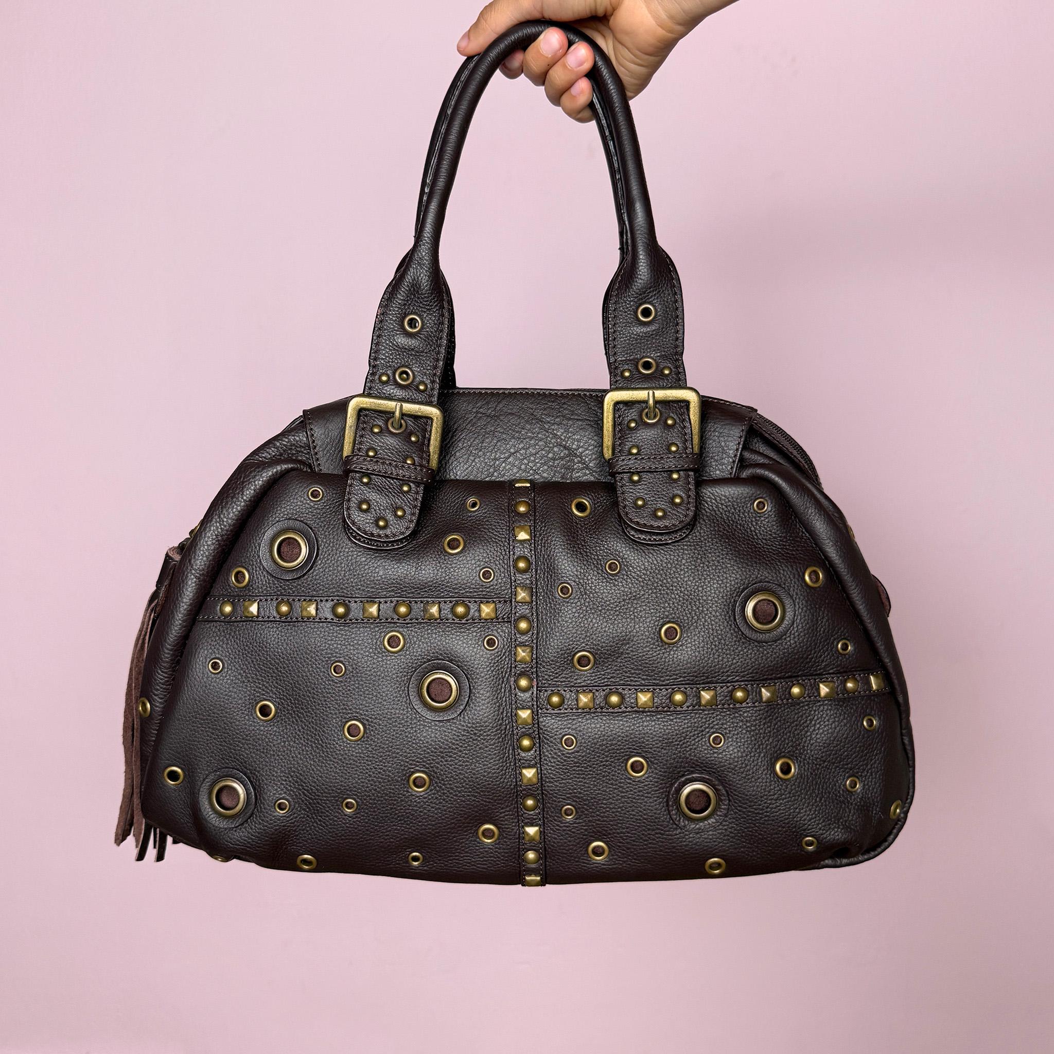 Vintage 2000s brown genuine leather shoulder bag. Features a large bowling-style silhouette, top zip closure, double handles, antique gold-tone studs, metal eyelets, and buckle details throughout. A bold Y2K Italian leather statement bag with a biker-boho grunge glam feel, spacious enough for everyday use while still feeling unique and visually strong. Excellent vintage condition.