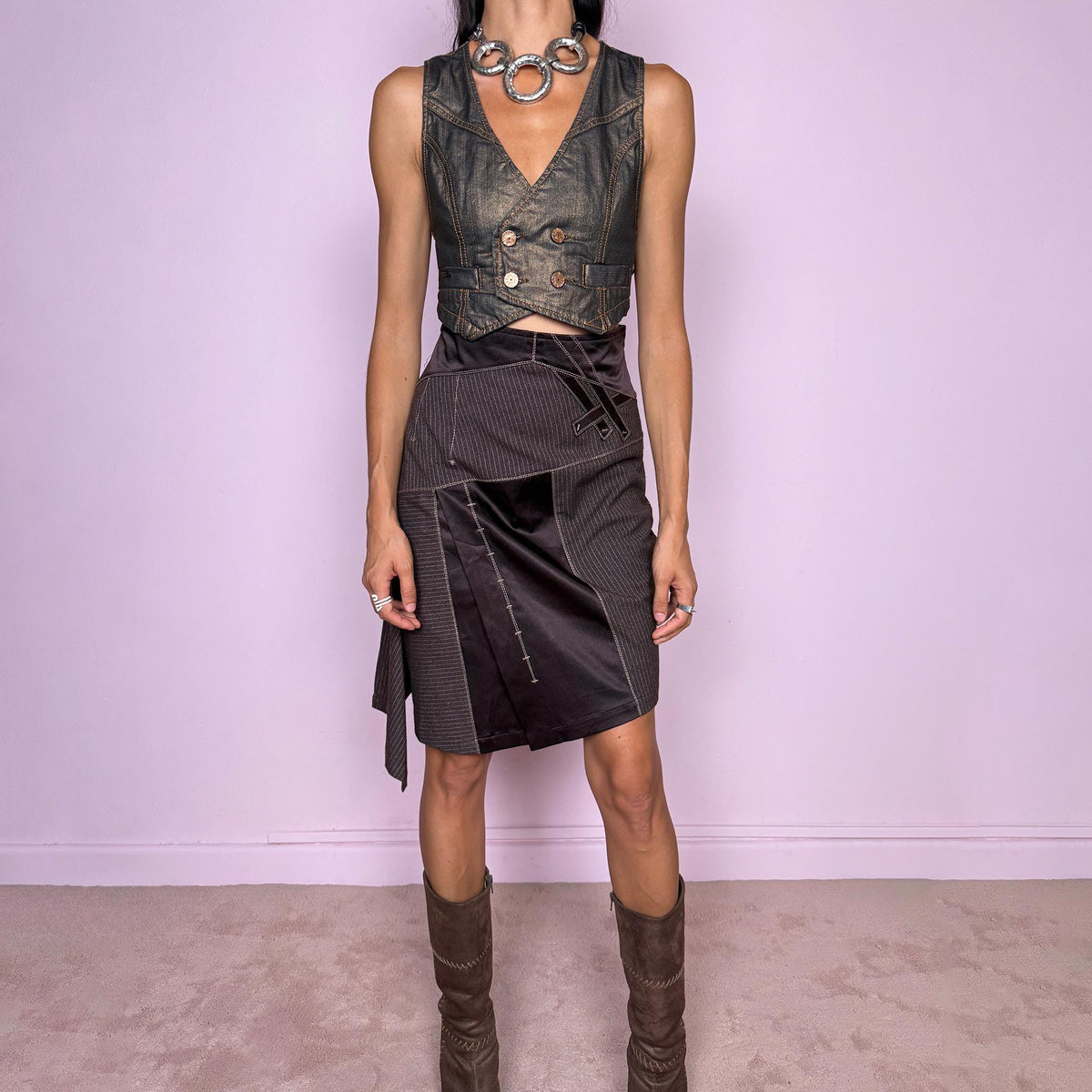 Vintage 2000s brown asymmetric midi skirt featuring a high-waisted, fitted silhouette with contrasting pinstripe and satin-like panels, sculptural draping along one side, and an elongated asymmetric hanging panel. Designed with contrast topstitching, decorative strap detailing, and a side zip closure. Non-stretch. The mix of tailored pinstripes, fluid draping, and deconstructed paneling gives it an avant-garde aesthetic. From a French brand.