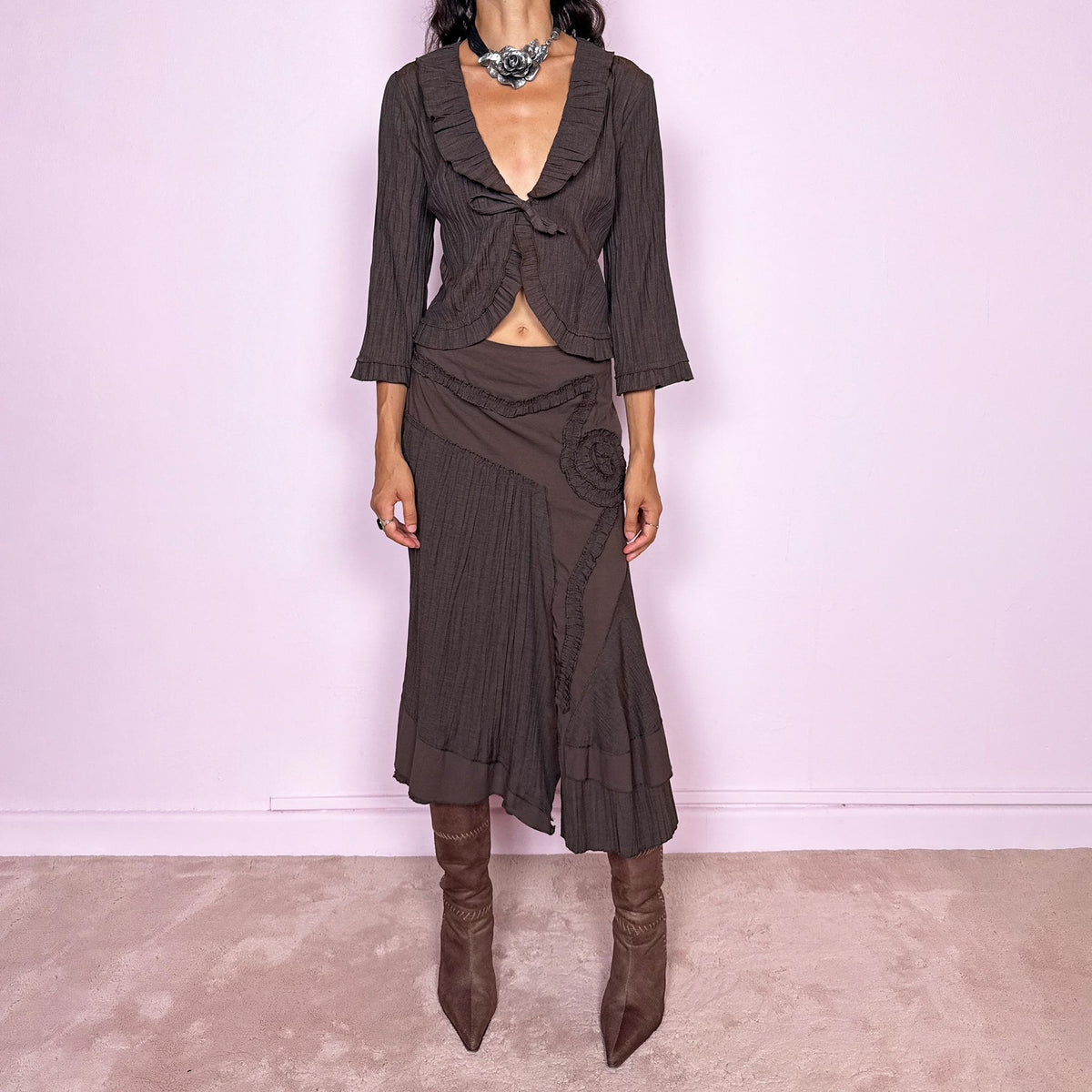 Vintage 2000s brown two-piece set featuring a fitted tie-front top with softly flared 3/4 sleeves and delicate ruffle trim, paired with a matching asymmetric midi skirt. The skirt combines fluid paneling, pleated inserts, ruffled appliqué detailing, and an irregular hem for a romantic deconstructed Y2K silhouette, with a side zip closure. Can be worn high-waisted for size S or slightly lower on the waist for size XS. Made from a non-stretch polyester and viscose blend.
