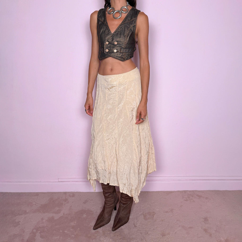 Vintage 2000s light cream-gold asymmetric midi skirt featuring a flared silhouette with an irregular handkerchief-style hem and a subtly crinkled, textured finish. Crafted from a structured, non-stretch blend of 53% polyamide, 32% cotton and 15% metallic fiber, with a 65% acetate and 35% viscose lining. Finished with a side zip closure. Can be worn mid-rise for size S or lower on the waist for size XS. From a German brand. Excellent vintage condition.