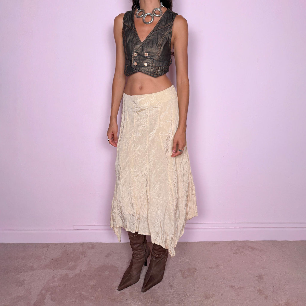 Vintage 2000s light cream-gold asymmetric midi skirt featuring a flared silhouette with an irregular handkerchief-style hem and a subtly crinkled, textured finish. Crafted from a structured, non-stretch blend of 53% polyamide, 32% cotton and 15% metallic fiber, with a 65% acetate and 35% viscose lining. Finished with a side zip closure. Can be worn mid-rise for size S or lower on the waist for size XS. From a German brand. Excellent vintage condition.