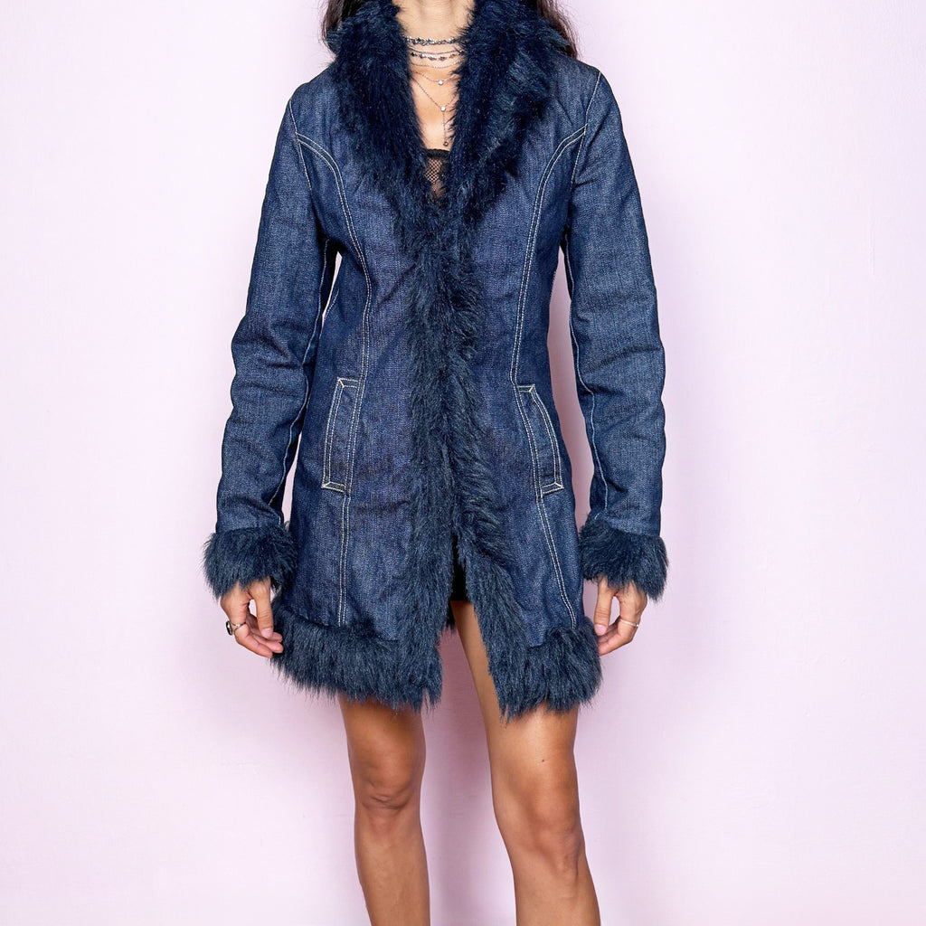 Vintage 2000s dark blue denim Penny Lane coat featuring deep navy faux-fur trim along the collar, front opening, cuffs, and hem. Designed with a fitted longline silhouette, contrast stitching, front pockets, and a button closure, blending 70s-inspired bohemian styling with a distinctly Y2K denim edge. Crafted from a cotton and polyester blend. From a Spanish brand. Excellent vintage condition.