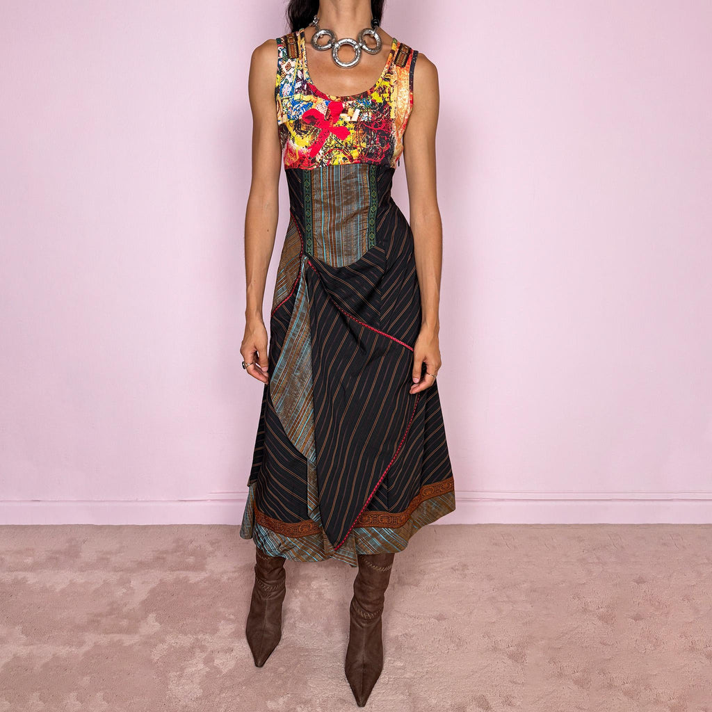 Vintage 2000s midi dress designed with a dramatic medieval-inspired avant-garde silhouette. It features a graphic bust panel with vivid abstract artwork, a fitted corset-effect waist with striped and patterned panels, a side zip closure, and a flowing asymmetric skirt with mixed striped fabrics, contrast trims, and layered draped sections for sculptural movement. Only the bust area has stretch, while the rest of the dress  A rare fantasy statement piece with a theatrical baroque feel.