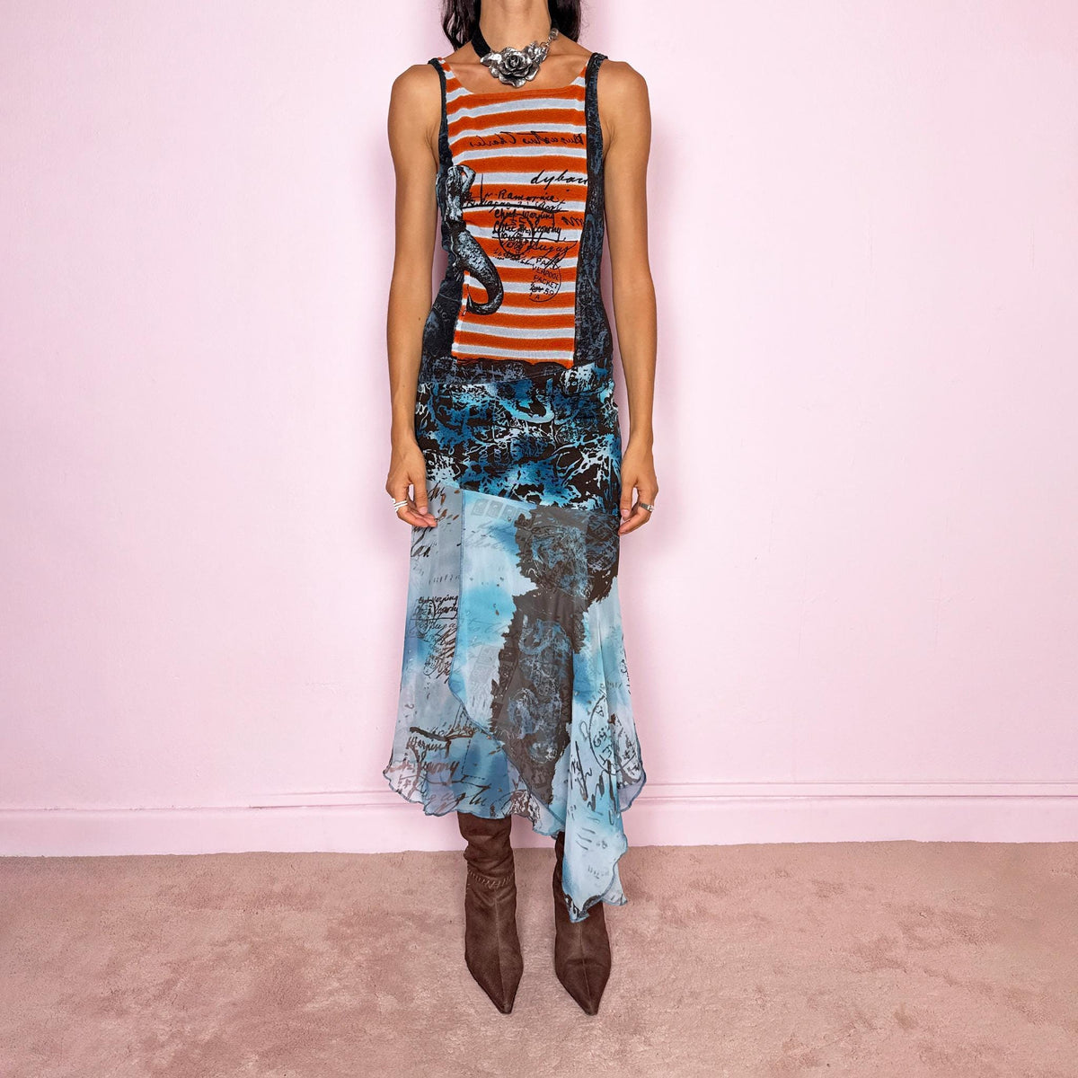 Vintage 2000s maximalist maxi dress featuring a mixed construction that combines fitted printed mesh through the upper body with semi-sheer mesh panels through the lower section, creating a fluid, layered effect. The graphic composition mixes striped, abstract, and handwritten-style motifs in burnt orange, brown, and vivid blue tones, finished with a dramatic asymmetric handkerchief hem for extra movement. A bold Y2K art-to-wear piece with an avant-garde, editorial feel.
