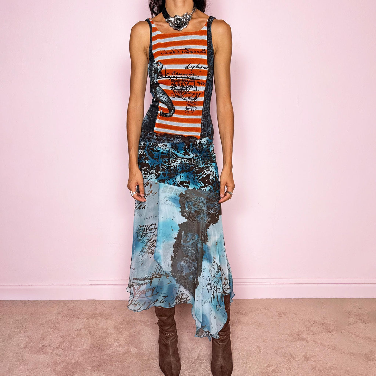 Vintage 2000s maximalist maxi dress featuring a mixed construction that combines fitted printed mesh through the upper body with semi-sheer mesh panels through the lower section, creating a fluid, layered effect. The graphic composition mixes striped, abstract, and handwritten-style motifs in burnt orange, brown, and vivid blue tones, finished with a dramatic asymmetric handkerchief hem for extra movement. A bold Y2K art-to-wear piece with an avant-garde, editorial feel.